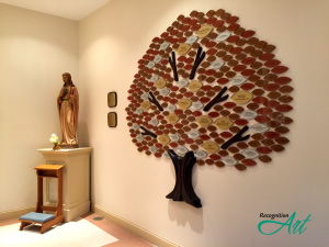 A sculpted wood donor recognition tree with Plexiglas leaves in earth tones categorized by size.