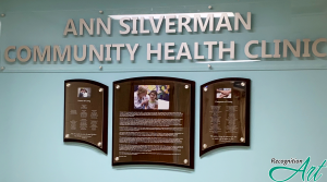 Acrylic header with metal letters that says Ann Silverman Community Health Clinic with a wood backer display with acrylic held by standoffs that display donors